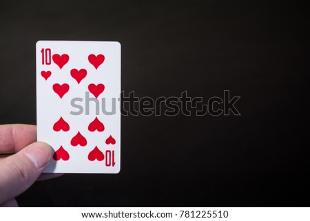 Abstract: man hand holding playing card ten on a black background