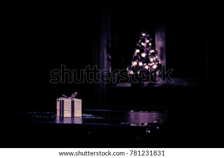 Red Christmas gift box and fir tree on snow. Christmas home decoration with snow and tree on a dark background with copy space. Selective focus. New Year attributes on background