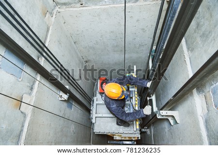lift machinist repairing elevator in lift shaft Royalty-Free Stock Photo #781236235