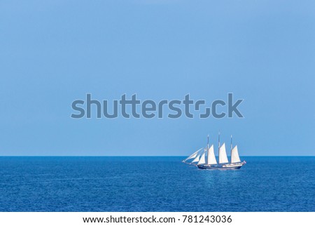Big white sailing ship with three mast moving  along rocky coast of Gotland, island in Baltic Sea in Sweden. Beautiful old large ship under bright sun. Romantic picture. Alone ship among wide sea.