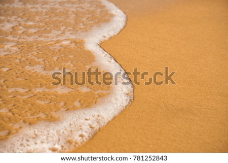 Background. A close-up of a wave runs over a sandy beach