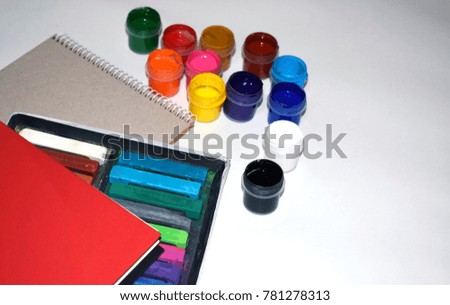 red notepad and bright colored paints on a white background