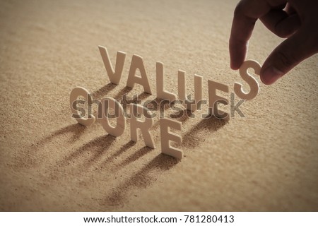 CORE VALUE wood word on compressed or corkboard with human's finger at S letter. Royalty-Free Stock Photo #781280413