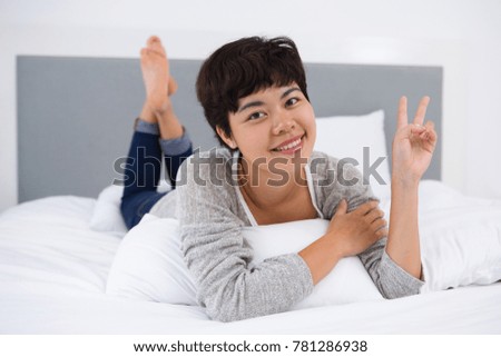 Positive woman gesturing to camera in bedroom