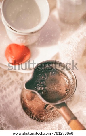 Two white coffee cups with heart shape chocolate on the plate and cezve with coffee, on the white shawl
