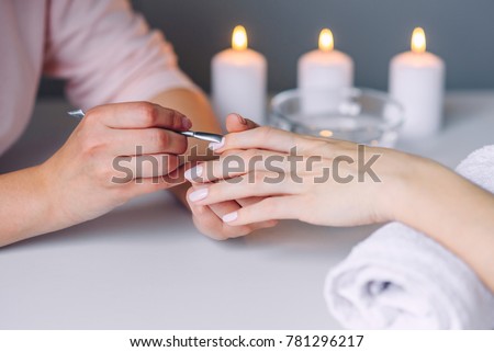 Nail care. Closeup of beautiful woman hands getting manicure in spa salon. Female manicurist cleaning cuticle with professional manicure pusher tool. Cosmetic procedure. Royalty-Free Stock Photo #781296217