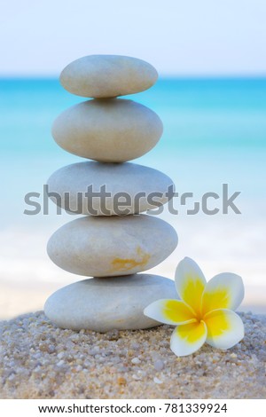 White Spa stones with frangipani flower on beach sand. Concept of balance and wellness.