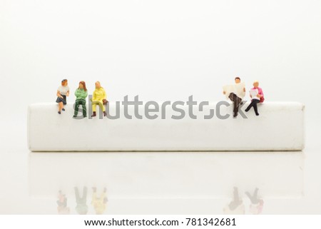 Miniature people, sitting on white block and read book. White block can write anything for  various occasions. Royalty-Free Stock Photo #781342681