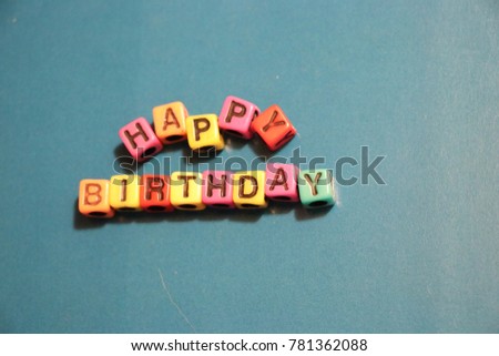 Happy Birthday party card invitation 3D words and letters spelled in blocks and beads on blue background.