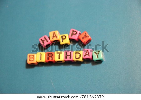 Happy Birthday party card invitation words and letters spelled in 3D blocks and beads with blue background.