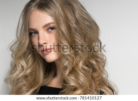 Curly long hair woman blonde hairstyle near white wall