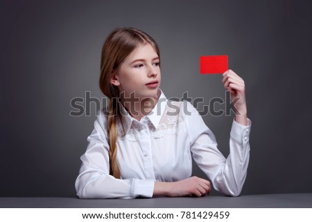 Beautiful teenage girl sitting showing red card in hand