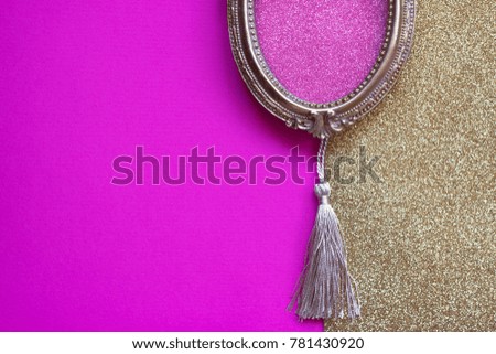 Vintage golden oval picture frame on pink and golden background, with copy space in the frame 