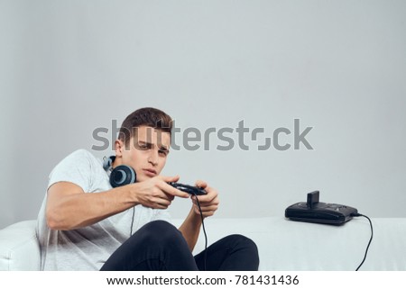 man is sitting on the sofa playing in the console on a light background                               