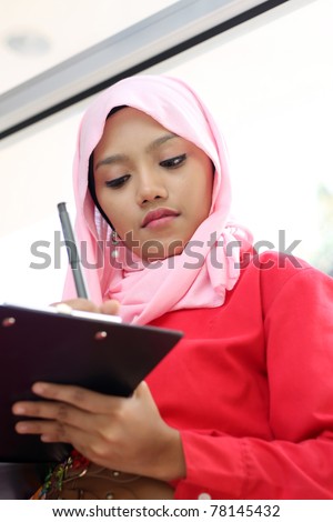 A young beautiful muslim girl writing on report file