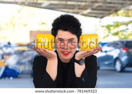 Asian man with box number 2018 for happy new year image.To the transport, automotive and everyone on blurry background.  Using life insurance or Health, business welcome new year photo.
