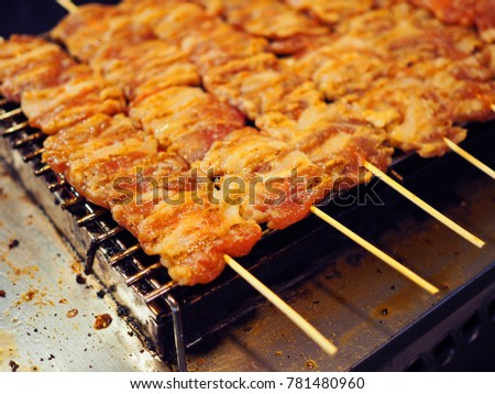 Raw pork, meat and fat, packed on bamboo stick, stacked altogether on charcoal grilling mesh, on dirty, fat stained cooking aluminum table, from Thai local traditional street food night market stall