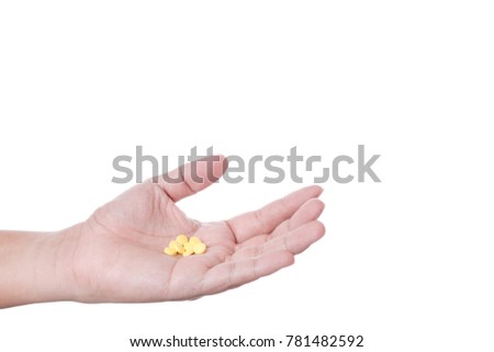 Hand holding yellow medical pill on white background