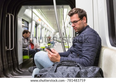 Casual man reading from mobile phone screen while traveling on metro. Wireless internet on public transport concept. Royalty-Free Stock Photo #781483759