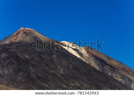An uphill view of the colourful Teide volcano in Teide National Park, Tenerife, Canary Islands. Pictured in the distance is a cablecar leading up to the 3718 m Teide peak, the tallest peak in Spain.