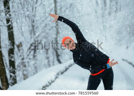 Girl wearing black sportswear workout on snow winter park background. Winter sports, outdoor fitness, workout, motivation concept.