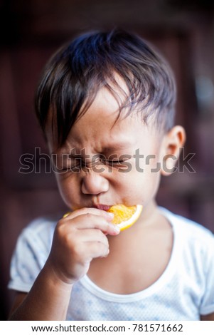 Asian child  pout biting sour lemon. Sour taste.  Royalty-Free Stock Photo #781571662