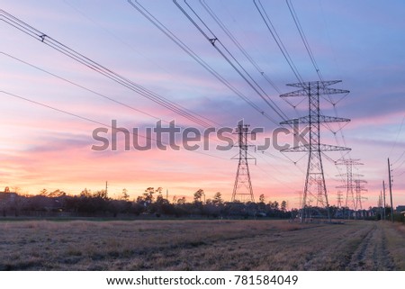 Industrial background group silhouette of transmission towers (or power tower, electricity pylon, steel lattice tower) at bloody red sunset. Texture of high voltage pillar, overhead power line at dusk
