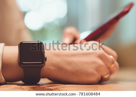 Picture Woman Working Modern Studio,Wearing Generic Design Smart Watch Hand.Female Finger Touching Screen Mobile Phone.Manage Work Process. Horizontal. Burred background. Film effects.
