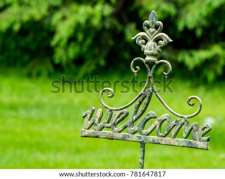 outdoors iron welcome sign with water drops in a natural setting