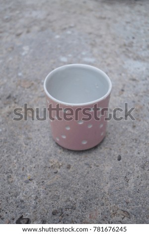 Pink and white porcelain handmade cup  on the concrete surface background. Cup in polka dots. Pottery design. Ceramic design. Place for the inscription, text.