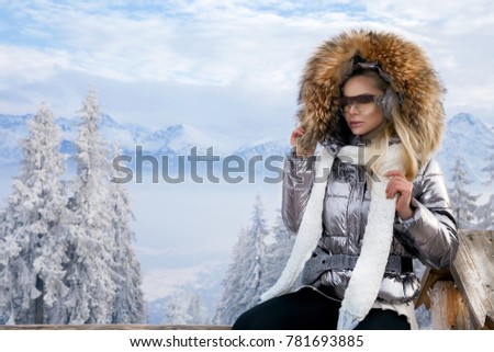 Young woman winter portrait. Winter fashion model with ski suit and goggles. Attractive young woman in wintertime outdoor. Mountains, white snow in magic winter day.