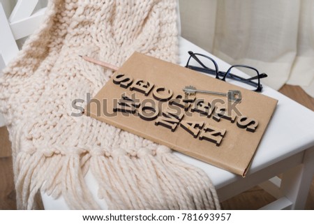 The book is wrapped in old paper and signed with wooden letters woman secrets, on the book key. White background chair in the interior of the house.