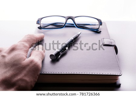 hand takes a notebook with glasses and a pen