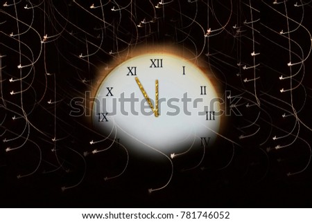 clocks on a dark background with lights showing five minutes until midnight - a new year begins