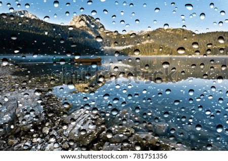 Lake through the window glass covered by raindrops 
