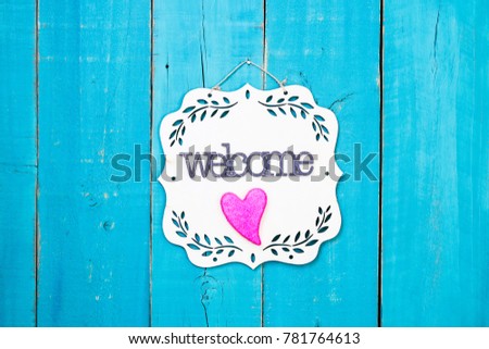 Welcome sign with pink heart hanging on antique rustic teal blue wood door; Valentines Day holiday, home and love concept background