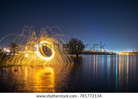 Showers of hot glowing sparks from spinning steel wool on the rock and beach. Burning and spinning steel wool fireworks on the floor