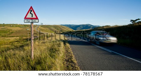 curvy road sign in rural country and speeding car