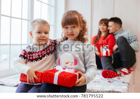 A little brother hugs and kisses his older sister against the background of happy parents. Family warmth and love. The psychology of a good family. mom and dad are happy looking at their children
