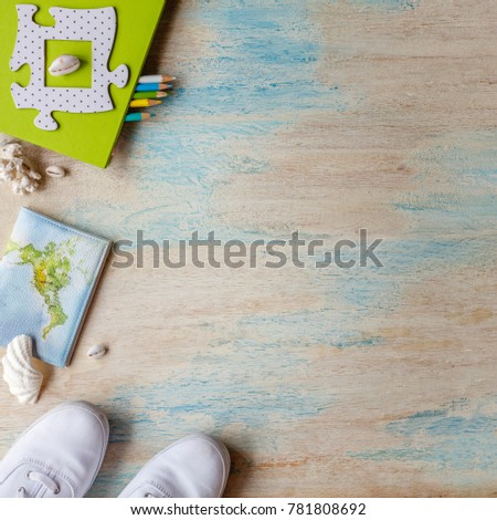 Travel concept background. Overhead view of traveler's accessories. White sneakers, passport, notebook, colored pencils, shells. White and blue washed wooden surface. Square image. With space