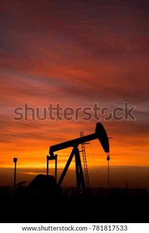 Silhouette of crude oil pump in the oilfield at sunset.
