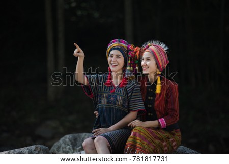 two young karen girls smiled and sit on the rock in the middle of the forest