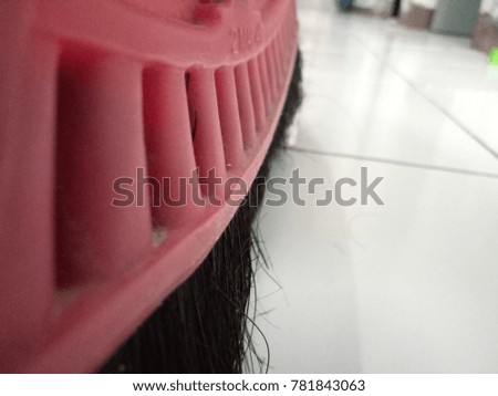 a black house broom and a white top above a white tile in a house from close range