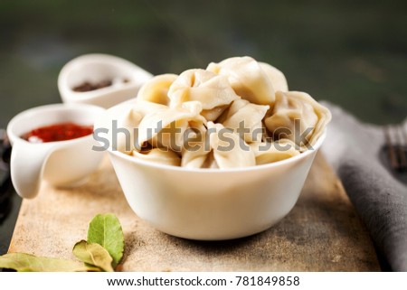 Traditional russian pelmeni, ravioli, dumplings with meat on concrete background. Russian food and russian kitchen concept. Selective focus
