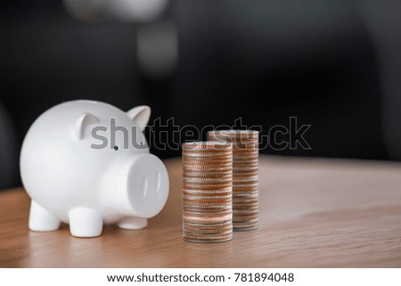 White piggy bank  and stack coins on wooden desk ,saving money for future investment concept