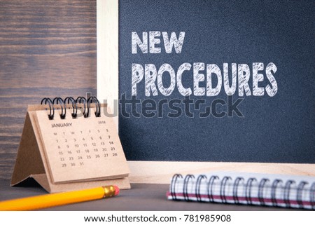 New Procedures concept. paper calendar and chalkboard on a wooden table