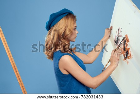 painter holds a canvas with a picture on a blue background, drawing                              