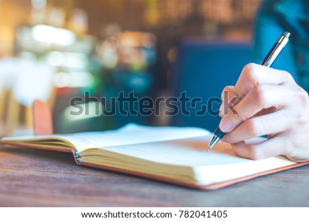 Woman hands with pen writing on notebook in the office.
