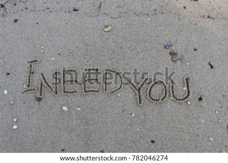 Handwriting  words "I NEED YOU." on sand of beach.