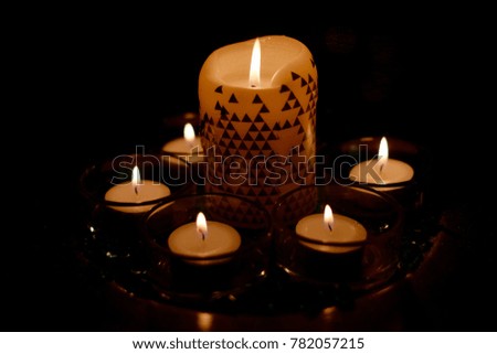 Tea candles and one big white candle, led lights background